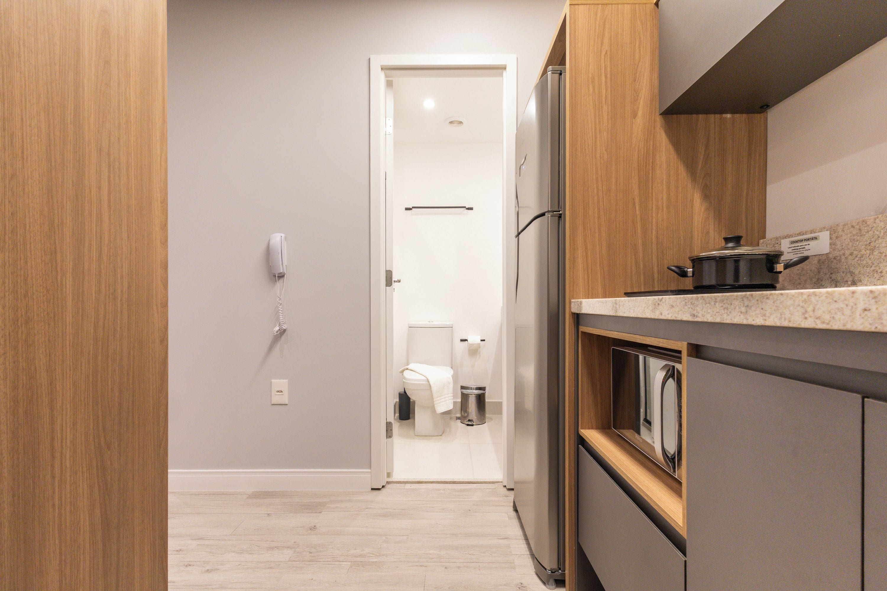 Een moderne keuken met een ingebouwde oven, een koelkast en een kookplaat, plus een draagbare sanitaire voorziening.