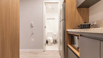 Een moderne keuken met een ingebouwde oven, een koelkast en een kookplaat, plus een draagbare sanitaire voorziening.