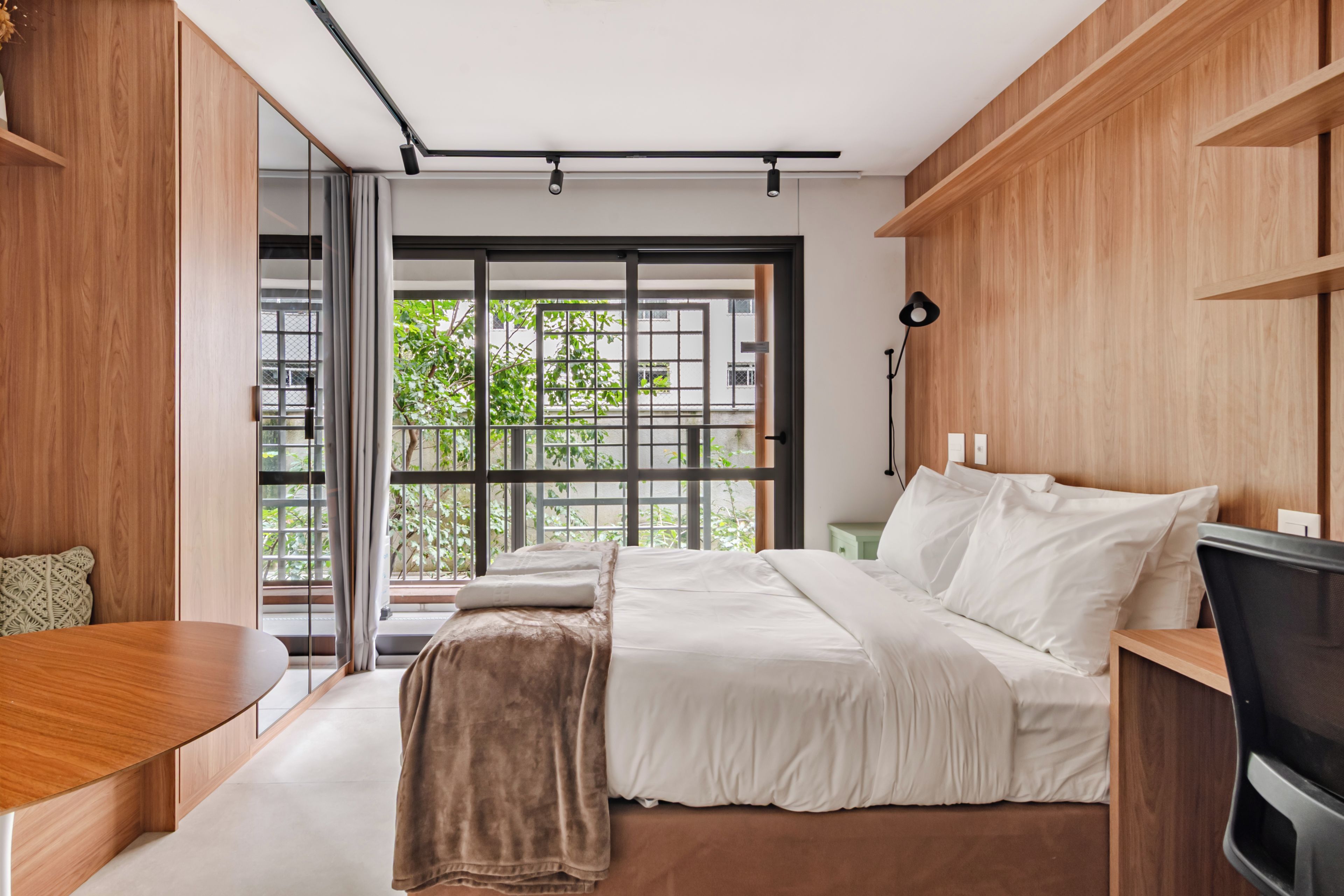 Quarto moderno com uma cama grande, uma escrivaninha e uma televisão.