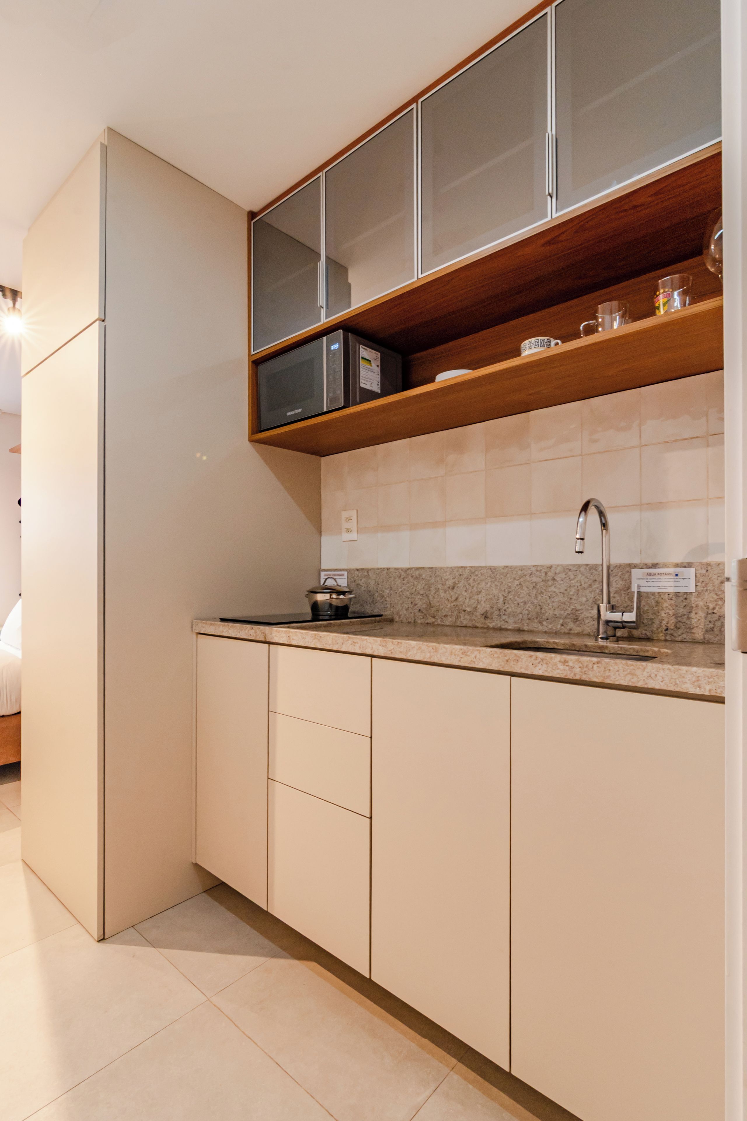Een moderne keuken met een ingebouwde magnetron, een spoelbak en een houten plank boven het aanrecht.