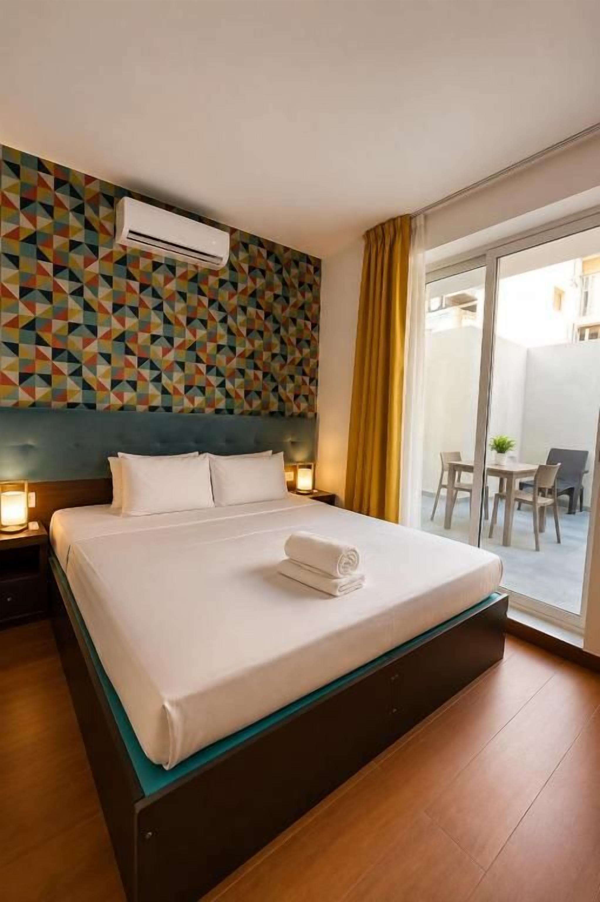 Habitación de hotel con cama, aire acondicionado de pared y vistas al exterior.