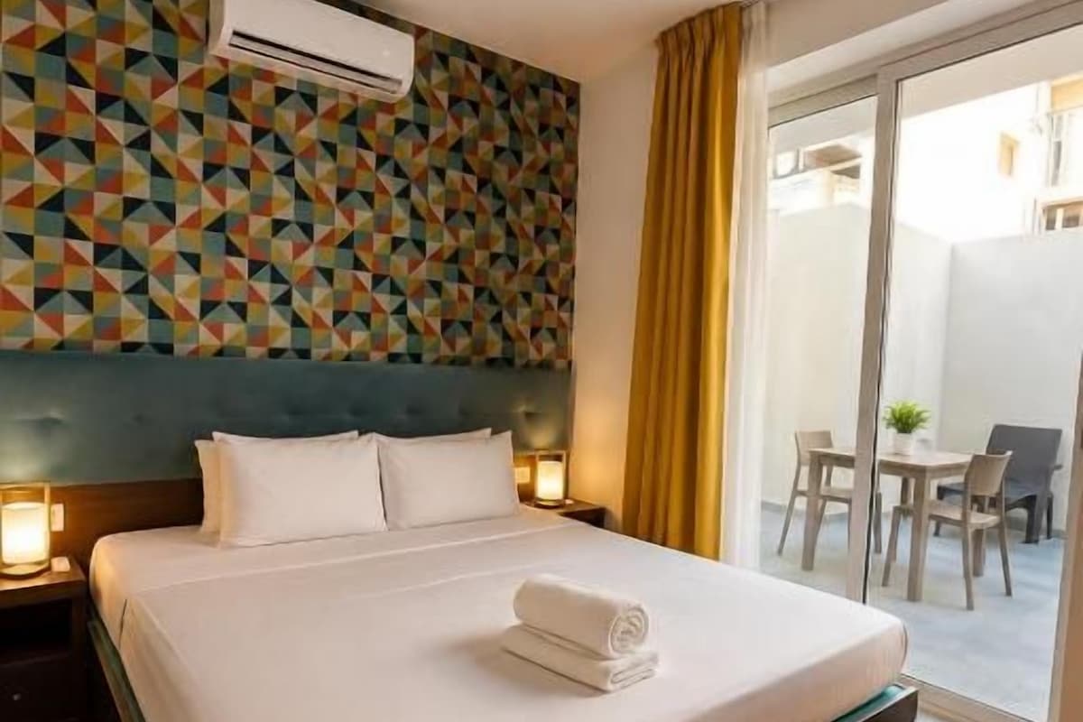 Quarto de hotel com cama, ar-condicionado na parede e vista para o exterior.