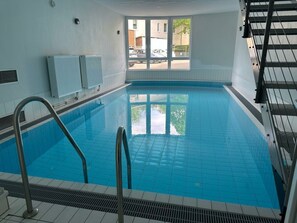 Ein Hallenbad mit Blick durch große Fenster nach draußen.