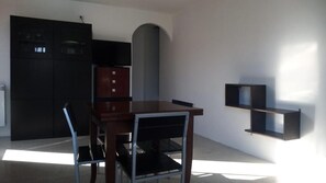 A dining area with a table and chairs, a kitchen with cabinets, and a wall-mounted shelf. - Holiday Home 'Mare E Monti' with Mountain View, Private Pool, and Air Conditioning (Petriolo)