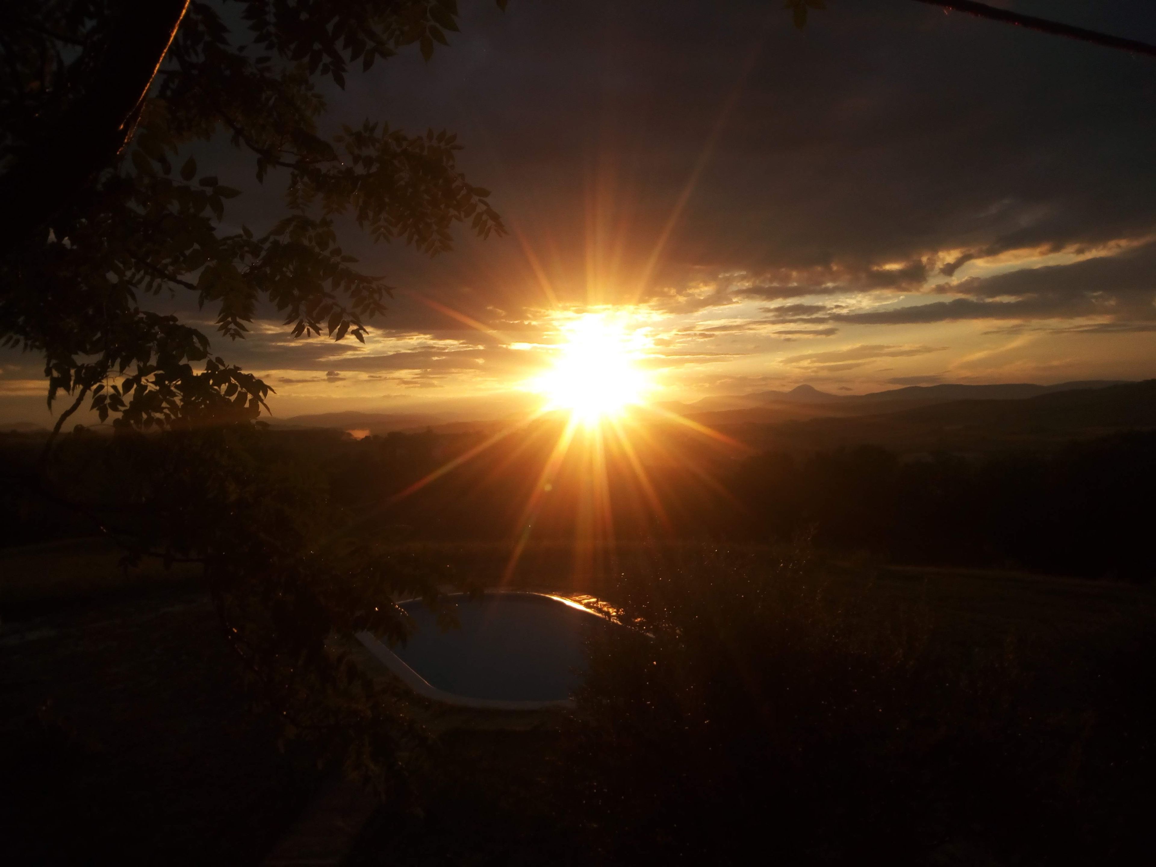A sunset over a landscape with a body of water and trees.