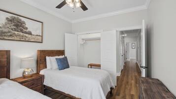 A bedroom with two beds, a ceiling fan, a nightstand with a lamp, and a painting on the wall.