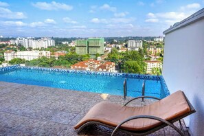 A pool with a view of surrounding buildings, a lounge chair, and a tiled floor. - 2-bedroom with Extra Room in Nairobi,Westlands Near Sarit, with pool, gym, cafes (Nairobi)