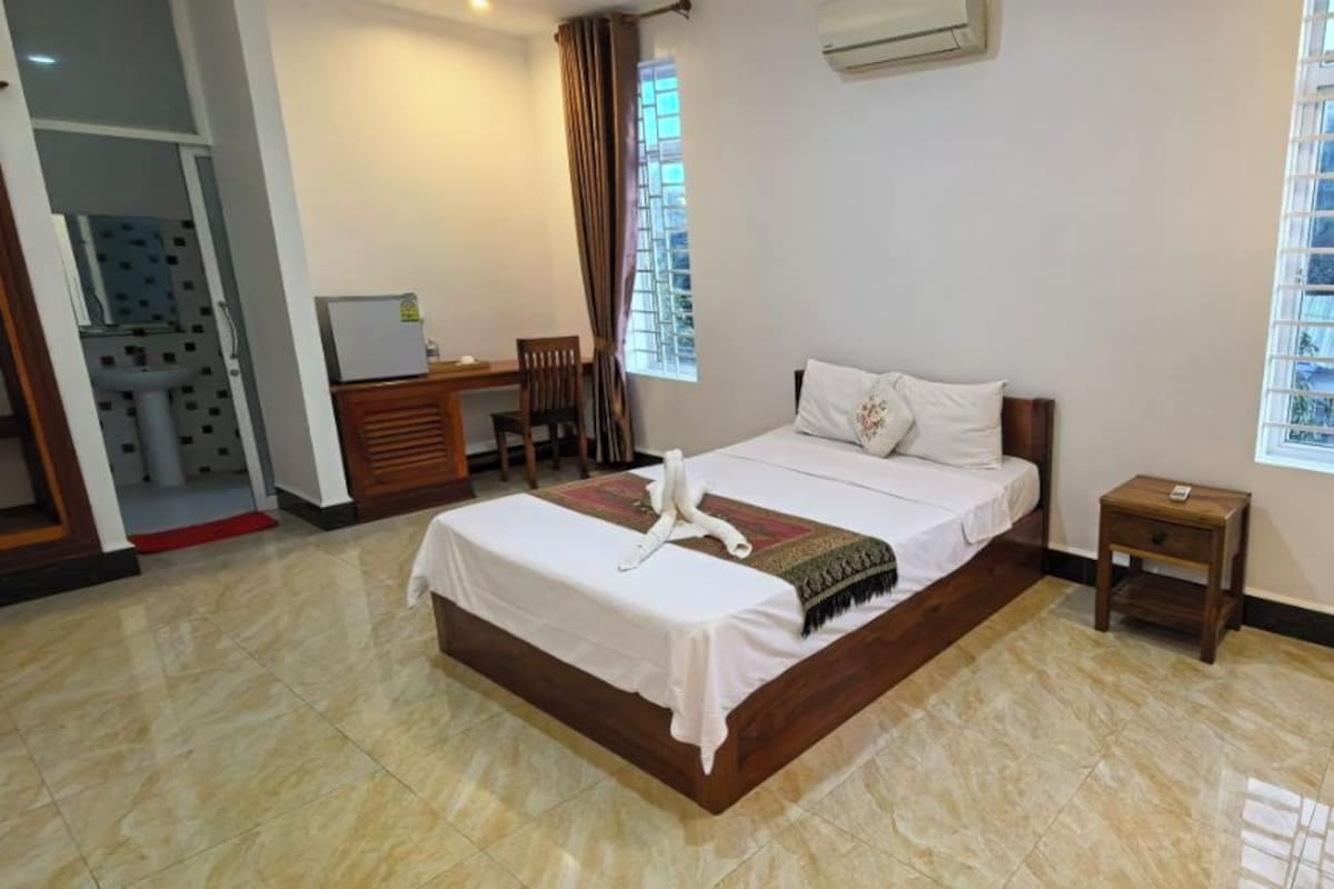 Una habitación de hotel con cama, mesita de noche y escritorio con silla.
