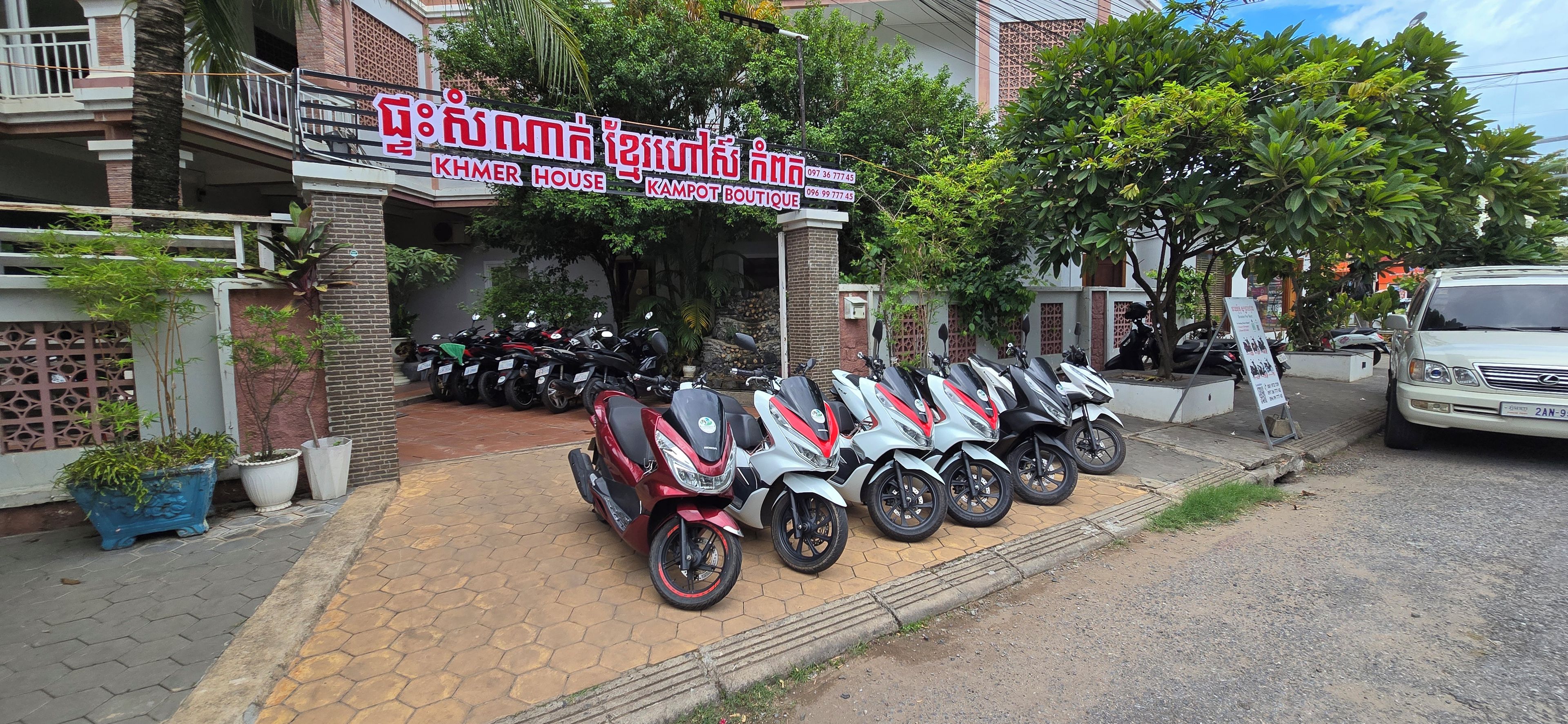 A building with a sign for 'KHMER HOUSE KAMPOUT BOUTIQUE' and a row of motorcycles parked in front.