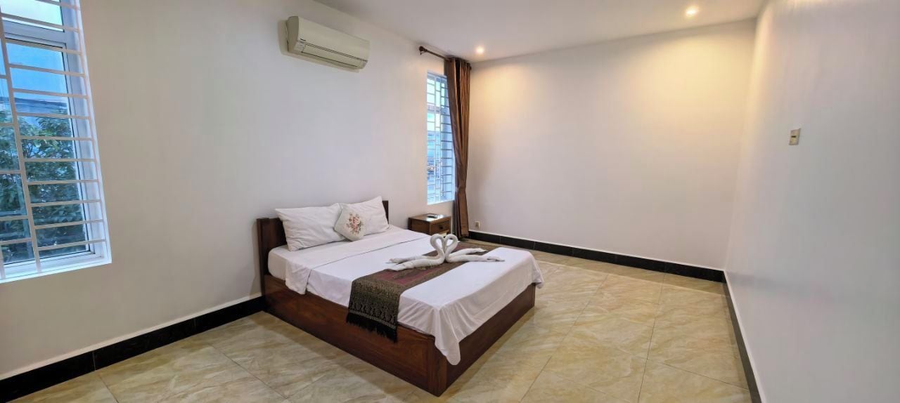 Une chambre à coucher comprenant un lit, une table de chevet, une fenêtre et un climatiseur fixé au mur.