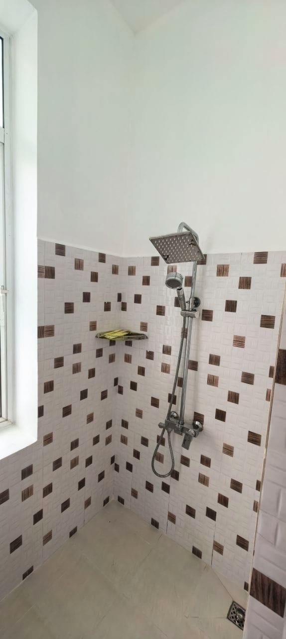 A corner shower with a handheld showerhead and a wall-mounted faucet.