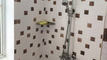A corner shower with a handheld showerhead and a wall-mounted faucet.