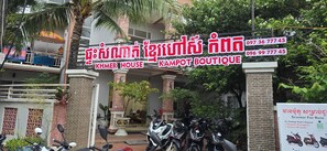 En byggnad med en skylt som visar texten ”KHMER HOUSE KAMPOT BOUTIQUE” och en anslagstavla som annonserar uthyrning av motorcyklar, med krav på att man ska kunna uppvisa pass och identitetskort.