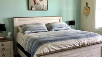 A bedroom with a bed, a ceiling fan, a nightstand, a lamp, and a wall-mounted hat.