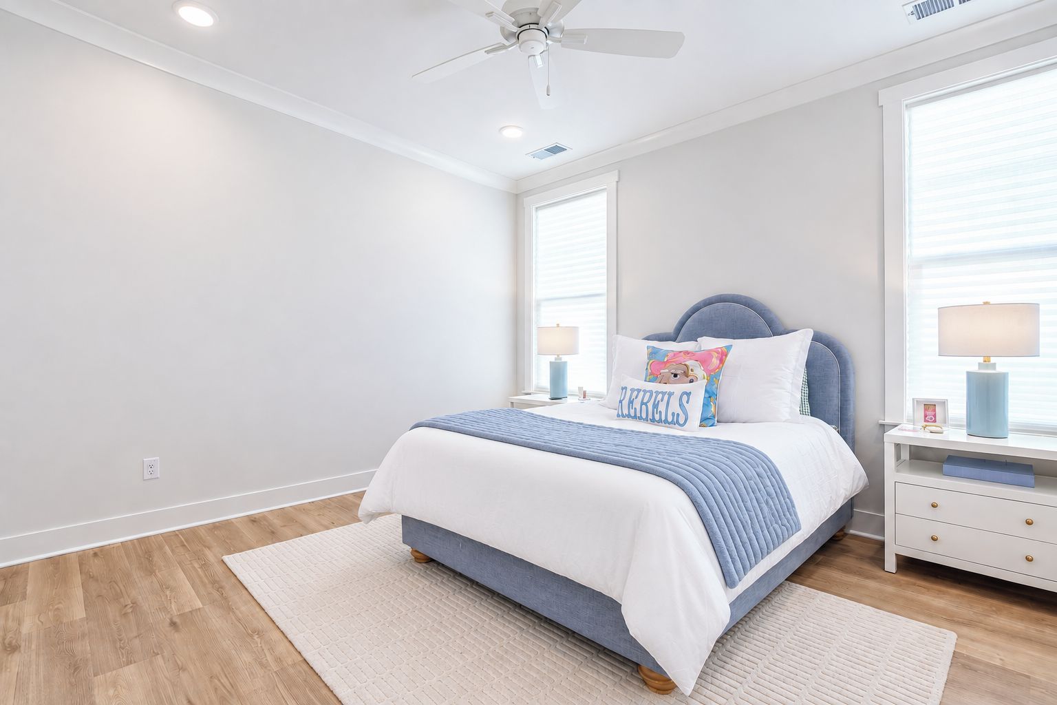 A bedroom with a bed, nightstands, a ceiling fan, and a window with blinds.