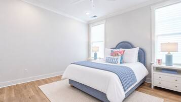 A bedroom with a bed, nightstands, a ceiling fan, and a window with blinds.