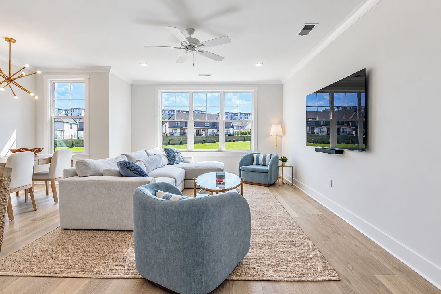 A modern living room with a sofa, armchairs, a coffee table, and a TV mounted on the wall.