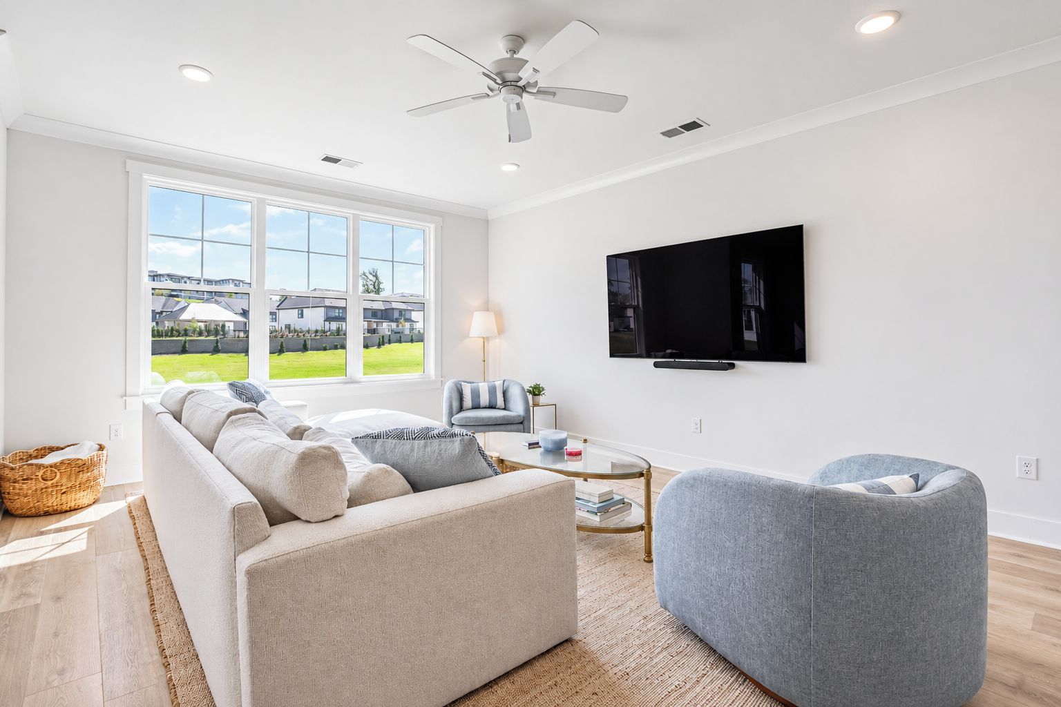 A modern living room with a sofa, armchair, and a flat-screen TV mounted on the wall.