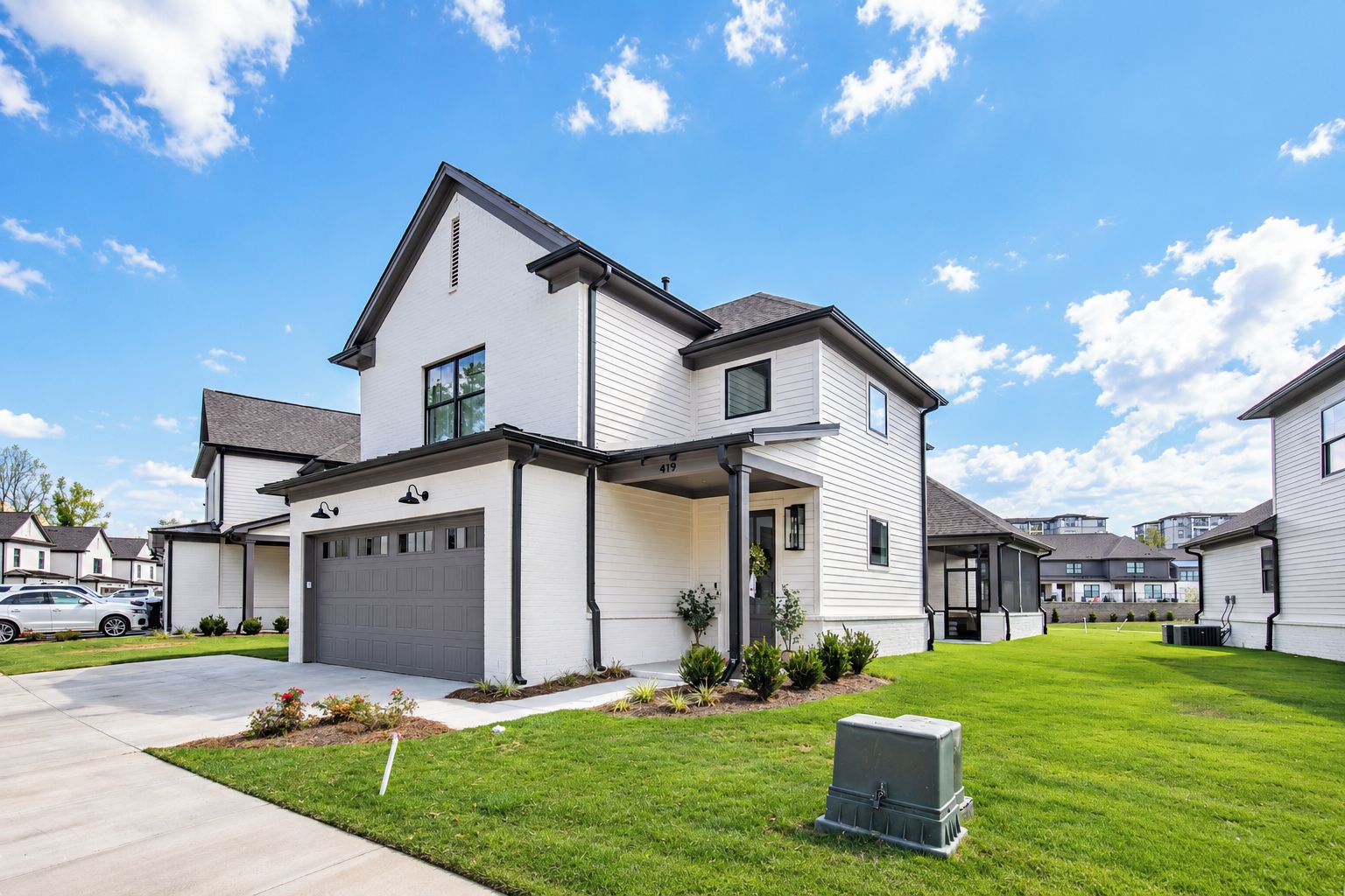 A two-story residential building with a garage, a covered porch, and a well-maintained lawn.