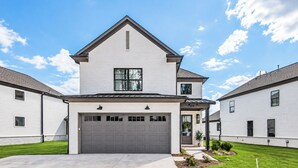 A two-story residential building with a garage, a covered porch, and a well-maintained lawn. - The Oak Grove, 3BR by Velvet Ditch Villas (Oxford)