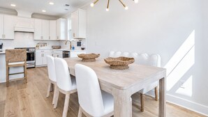 A modern kitchen with white cabinets, a wooden dining table, and a unique chandelier. - The Oak Grove, 3BR by Velvet Ditch Villas (Oxford)