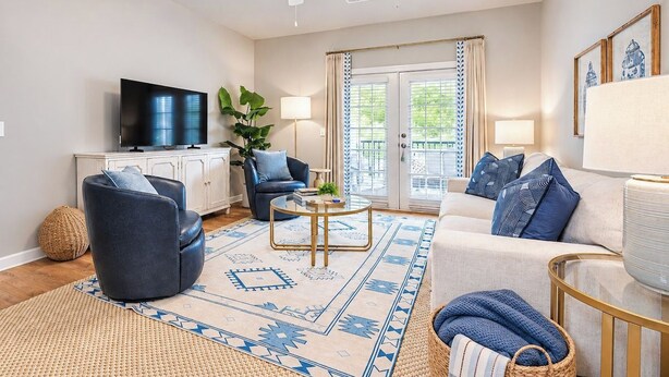 A living room with a flat-screen TV, a ceiling fan, a sofa, a coffee table, and a patterned rug. - The Rebel Landing, Pool+3BR by Velvet Ditch Villas (Oxford)