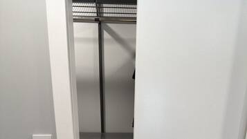 A narrow hallway leading to a room with a bunk bed, a small shelf, and a light switch on the wall.
