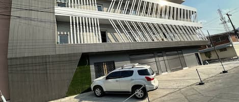 A modern building with a white car parked in front.