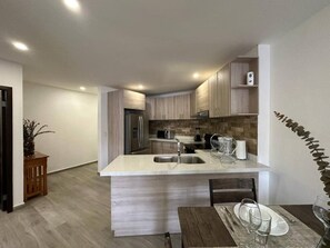 A modern kitchen with a central island, stainless steel appliances, and a dining area with a table set for two.