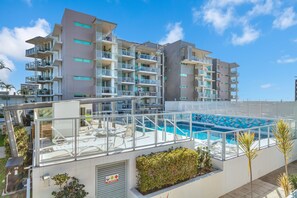 A multi-story hotel with a rooftop pool area, outdoor seating, and a no-smoking sign. - Palm and Sea Walkable Beachside Stay with Pool and Spa (Palm Beach)