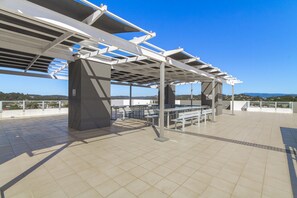 An outdoor terrace with a pergola structure, seating arrangements, and a view of the landscape. - Palm and Sea Walkable Beachside Stay with Pool and Spa (Palm Beach)