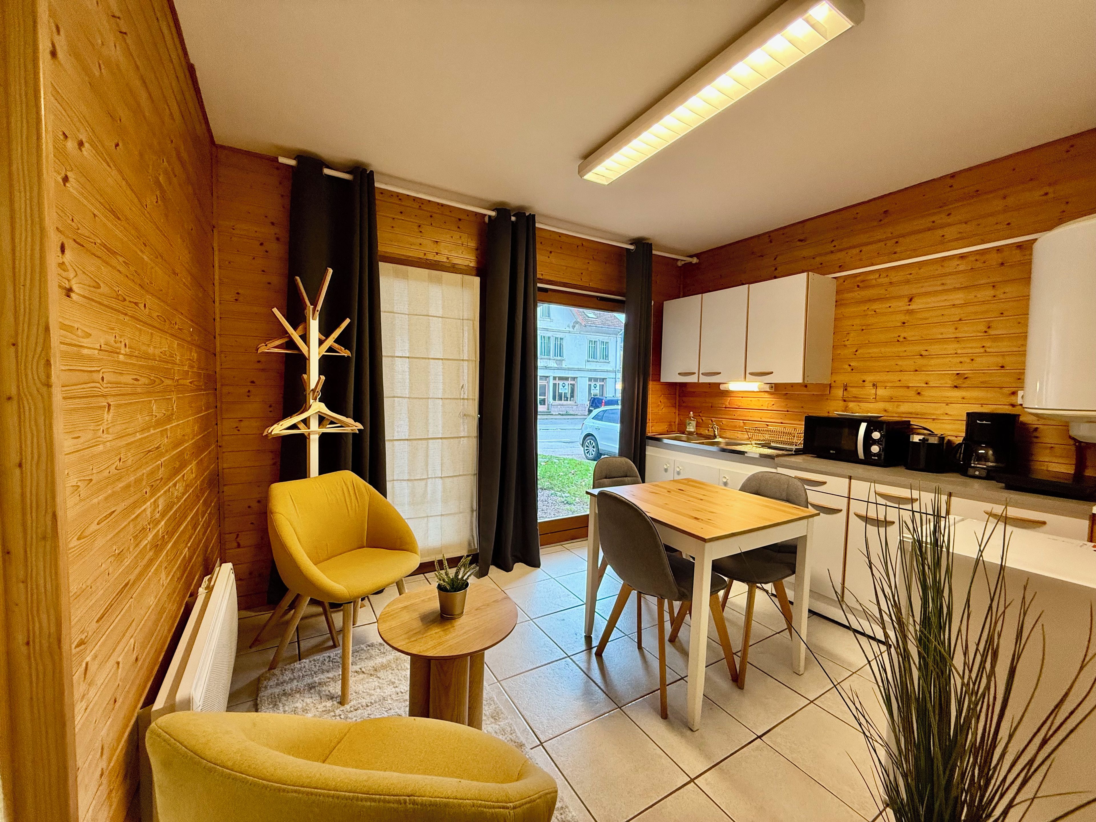 Un espace de vie compact comprenant un coin repas, une kitchenette et une vue sur la rue.