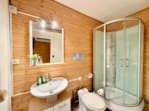 A wooden-paneled bathroom with a sink, mirror, toilet, and glass-enclosed shower. - "The Mountain Retreat," between the lake and downtown (Xonrupt-Longemer)