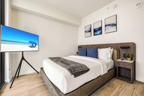 Ein modernes Schlafzimmer mit einem Bett, einem Fernseher und Kunstwerken an der Wand.
