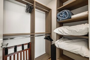 Ein begehbarer Kleiderschrank mit Holzregalen, einer Kleiderstange und einem Metallgestell.
