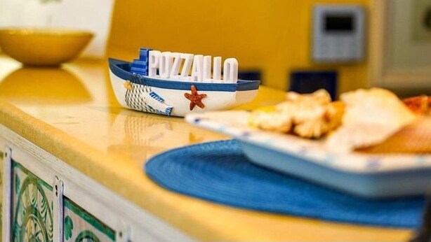 Uma bancada de cozinha com um pequeno recipiente em formato de barco identificado com 'PIZZA' e um prato de comida.