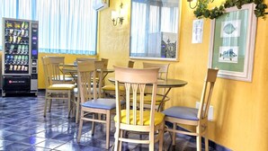 Uma sala de jantar com paredes amarelas, uma janela grande e uma máquina de vendas.