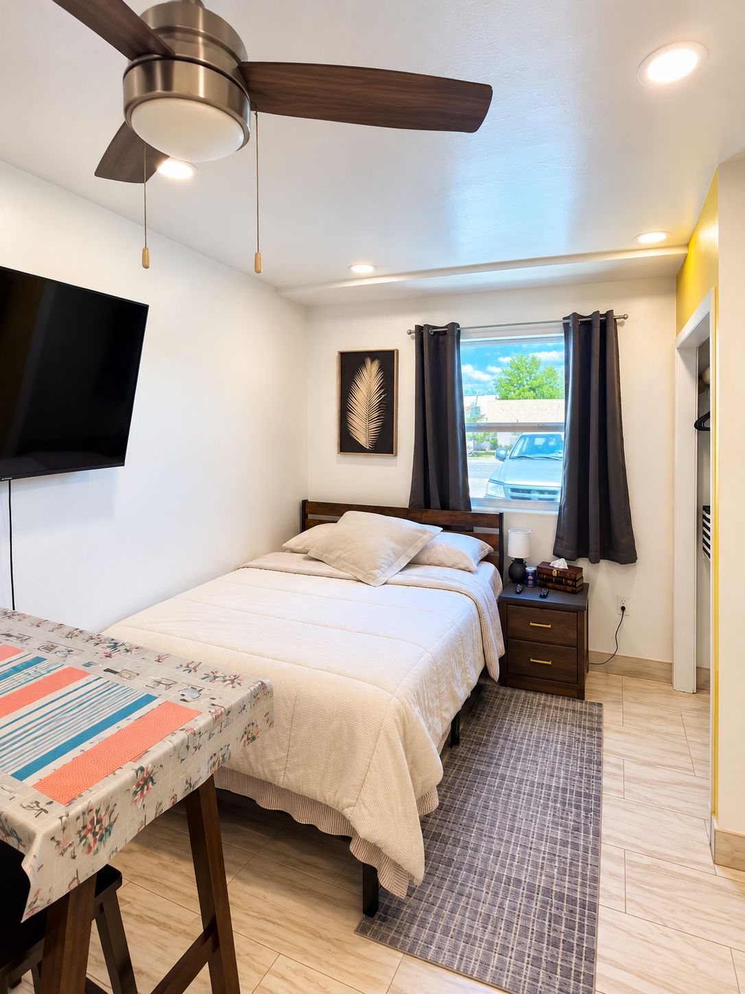 A bedroom with a bed, bedside table, lamp, and a ceiling fan.