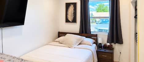 Une chambre à coucher avec un lit, une table de chevet, une lampe et un ventilateur de plafond.