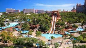 Een resort met diverse zwembaden, palmbomen en een grote glijbaan.