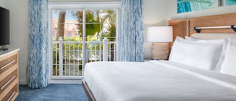 A hotel room with a bed, a television, a dresser, and a window with curtains.
