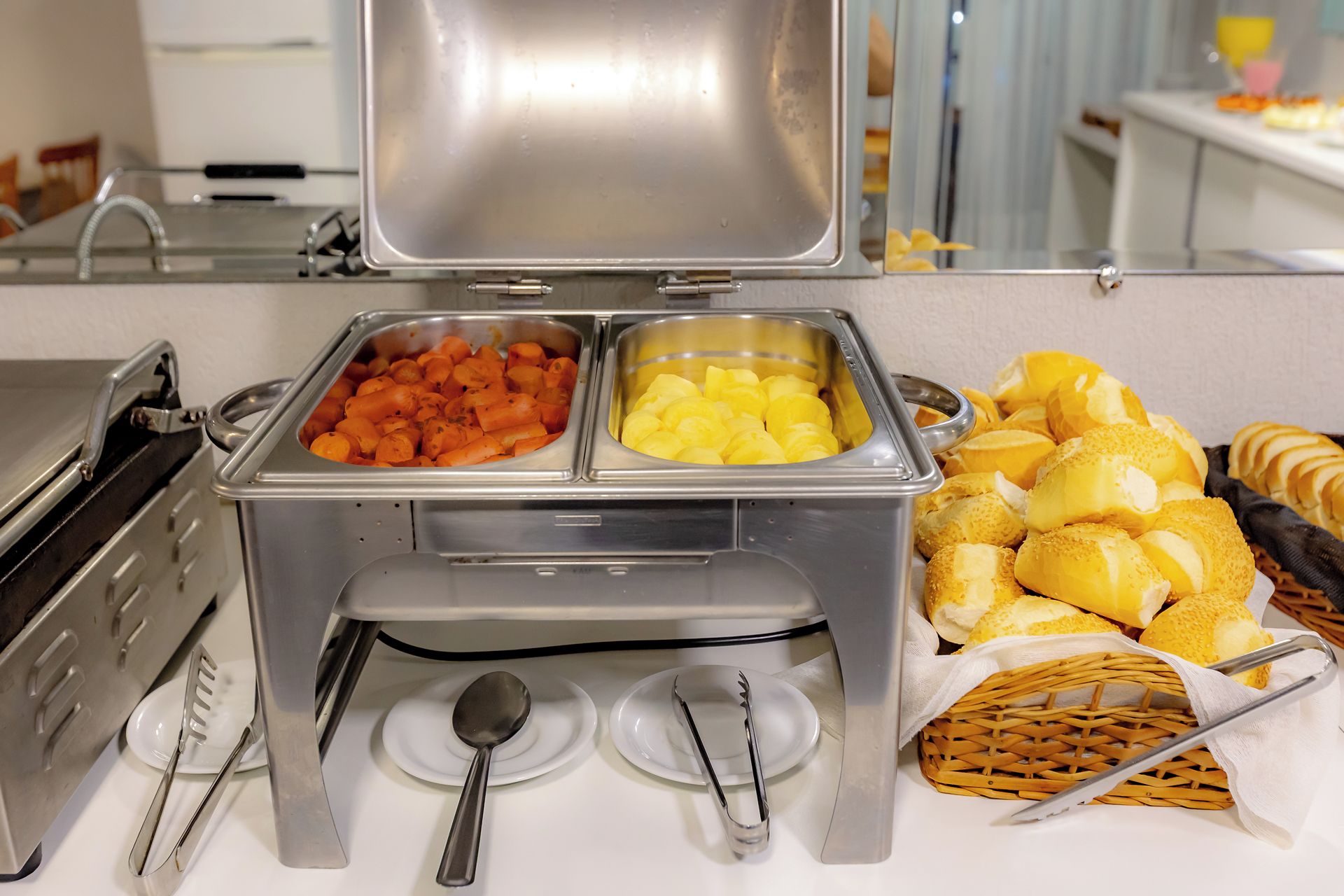 Disposição de buffet com diversos alimentos e utensílios.