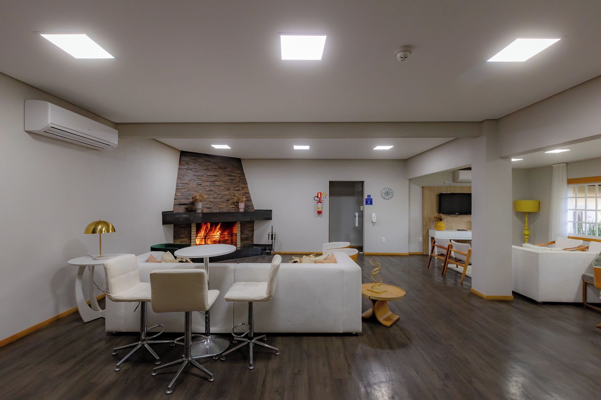 Una sala de estar moderna con chimenea, muebles blancos y un comedor.