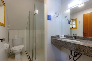 A modern bathroom with a glass-enclosed shower, a toilet, and a granite countertop sink with a mirror. - Alineville By Candeias (Canela)