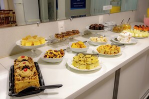 Un bufé con diversos postres, como pasteles, galletas y fruta.