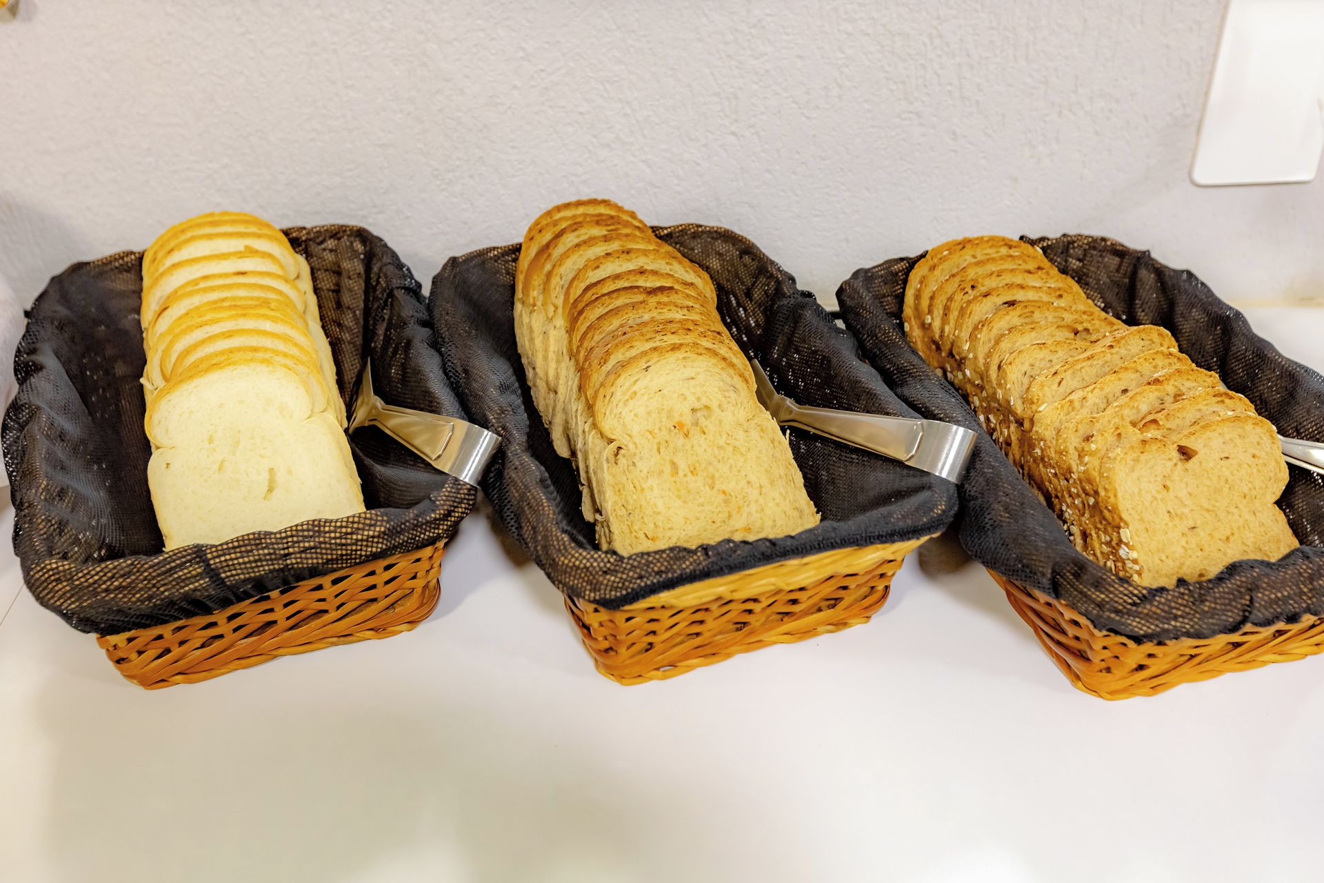 Three wicker baskets containing sliced bread.
