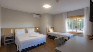 Een hotelkamer met twee bedden, een bureau en een raam met gordijnen.