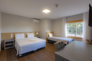 A hotel room with two beds, a desk, and a window with curtains. - Alineville By Candeias (Canela)