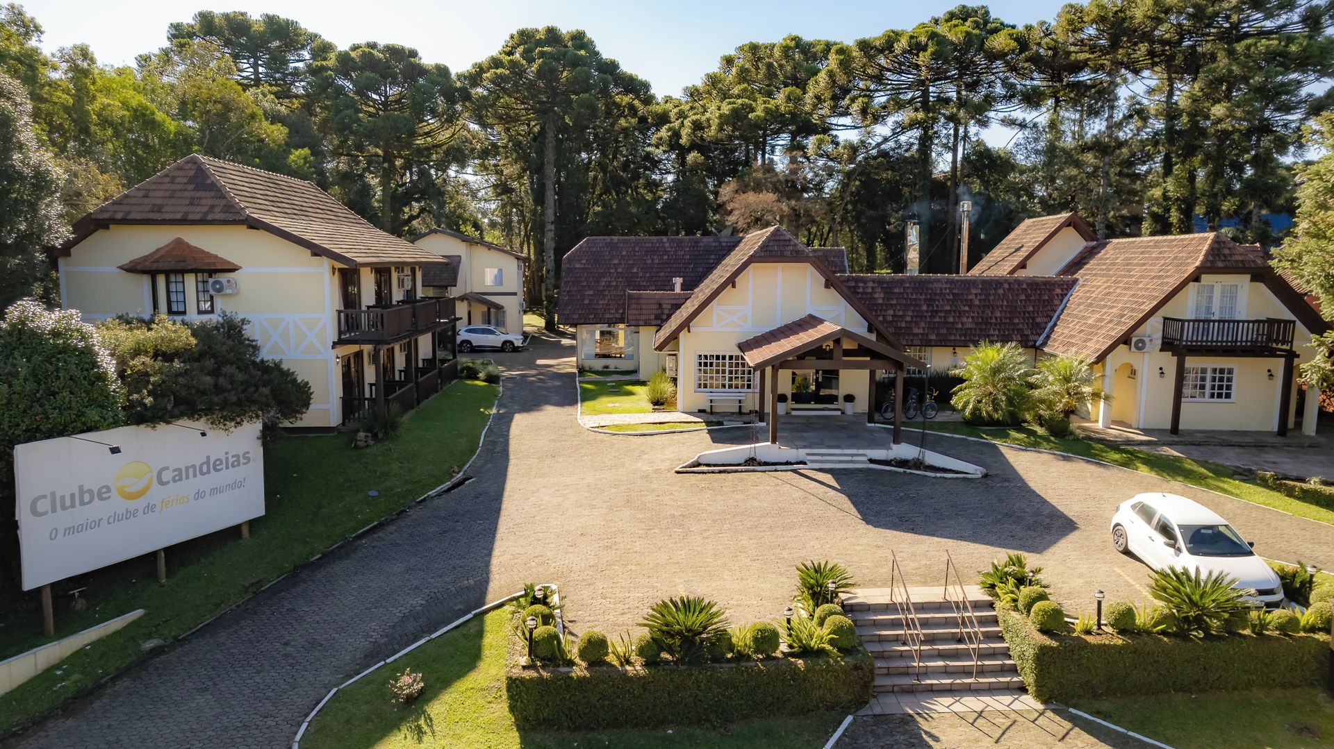A residential area with multiple houses, a paved driveway, and a sign for 'Clube Candeias.'