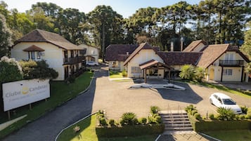 A residential area with multiple houses, a paved driveway, and a sign for 'Clube Candeias.'